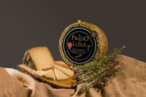 Queso artesanal Prado de Llera con romero, pieza entera y corte presentado con hierbas aromáticas.